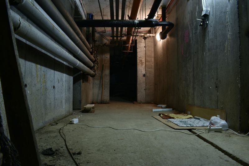 Dark basement corridor with exposed pipes along the wall