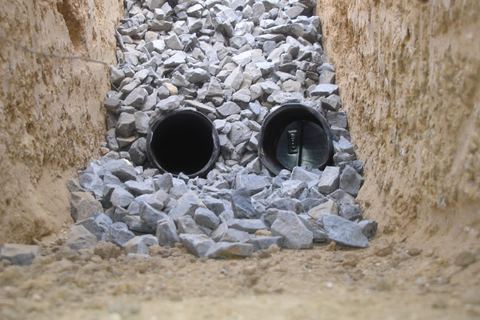 Narrow French drain trench with gravel layers