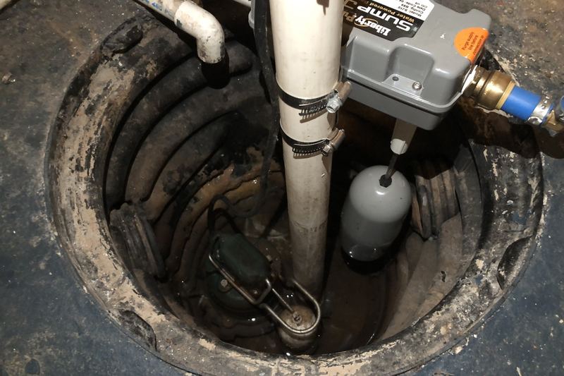 Newly installed sump pump in a basement sump pit with PVC discharge pipe